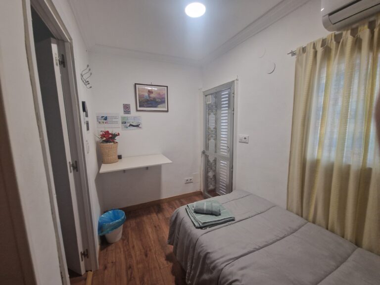La habitación cuenta con una cama individual, un escritorio y una ventana con cortinas