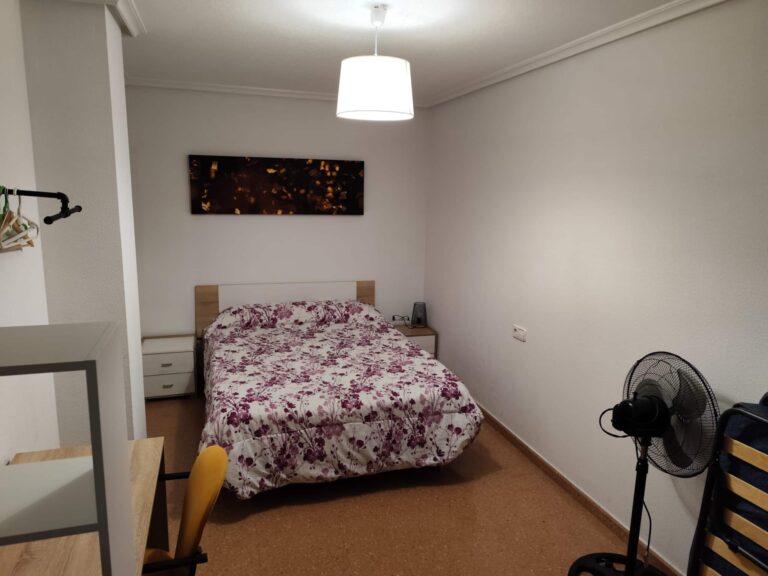 Una habitación con una cama y un ventilador