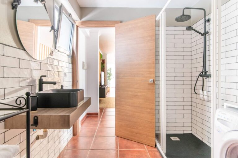 Bano con ducha, lavabo y espejo redondo