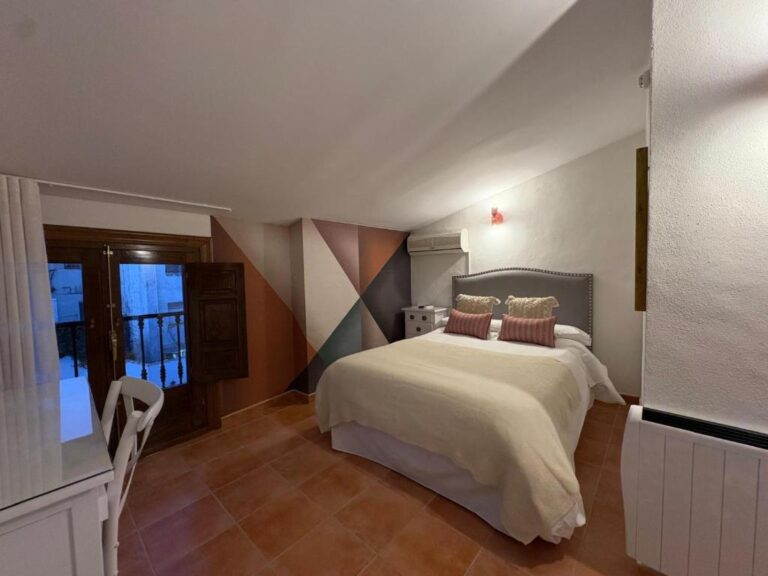 La habitación principal de este alojamiento en Jaén presenta un dormitorio con una cama doble, cubierta con una sábana