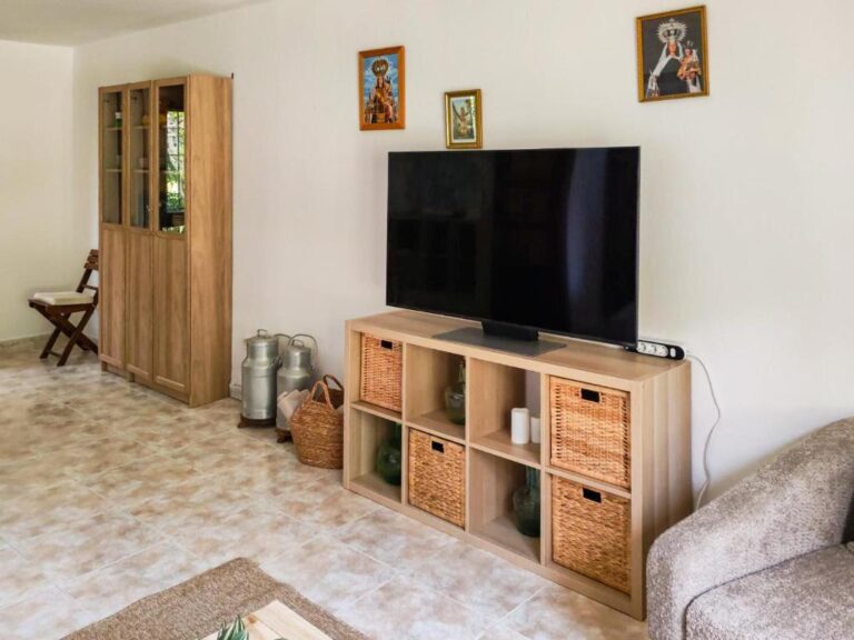 Un salón de un alojamiento en Cantabria, con un televisor de pantalla plana y un mueble de madera con cajones de mimbre