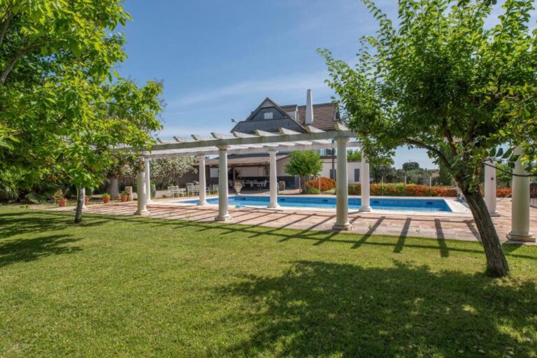 Una terraza con un pergola y una piscina, en un alojamiento ubicado en Montoro