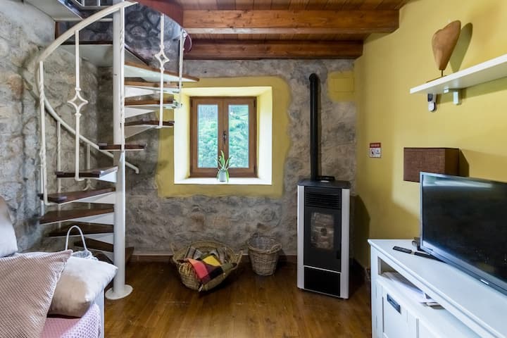 La estancia es un dormitorio con una cama, una escalera de caracol y una ventana con vista a un bosque