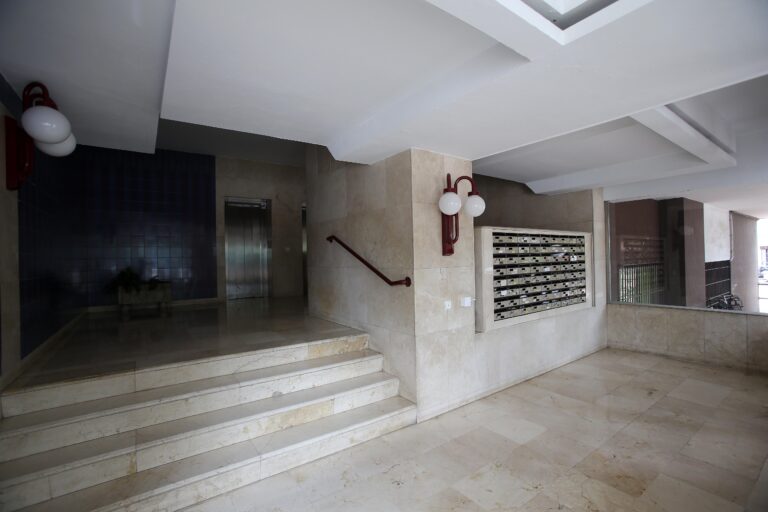 Una escalera interior de un alojamiento ubicado en Sevilla, con una pared de paredes de piedra y una barandilla de metal