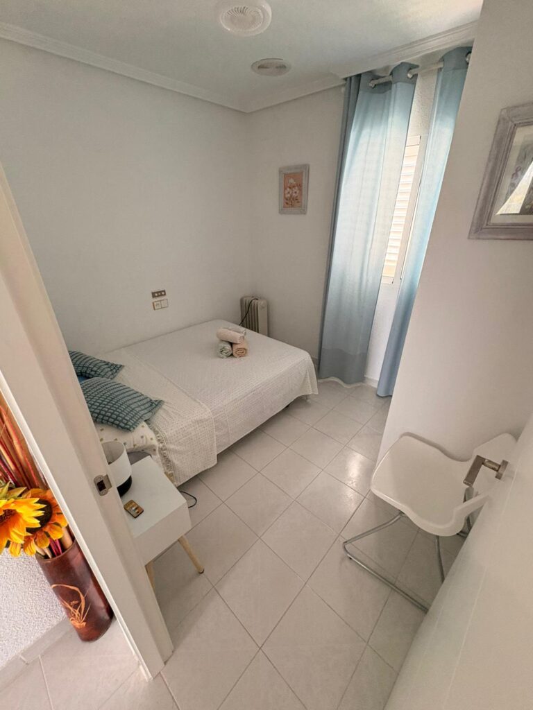 Una habitación pequeña con una cama y una silla