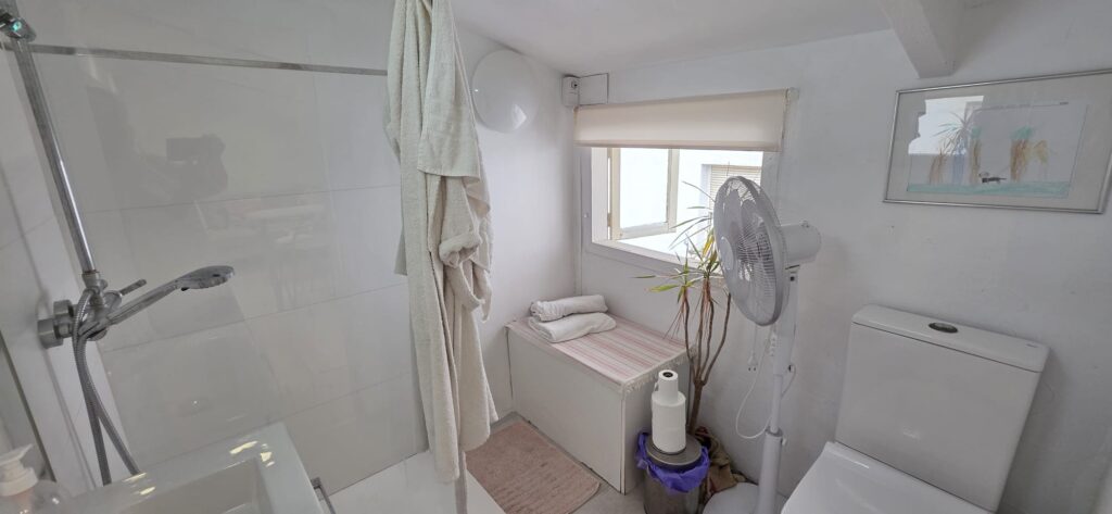 Bano con ducha, lavamanos, inodoro, lavadora, secadora, bidet, lavavajillas, toallas, jabon, champu, gel, papel