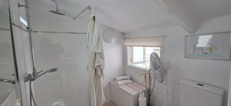 Un baño con ducha, con un bañador de ducha, un asiento de ducha y un espejo