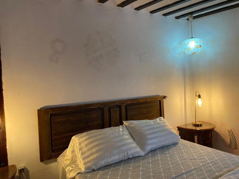 La habitación cuenta con una cama doble, una mesita de noche y una lámpara de mesa