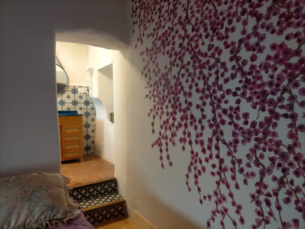Una pasillo con escaleras en un alojamiento ubicado en Ciudad Real. Se observa una decoración floral en la pared
