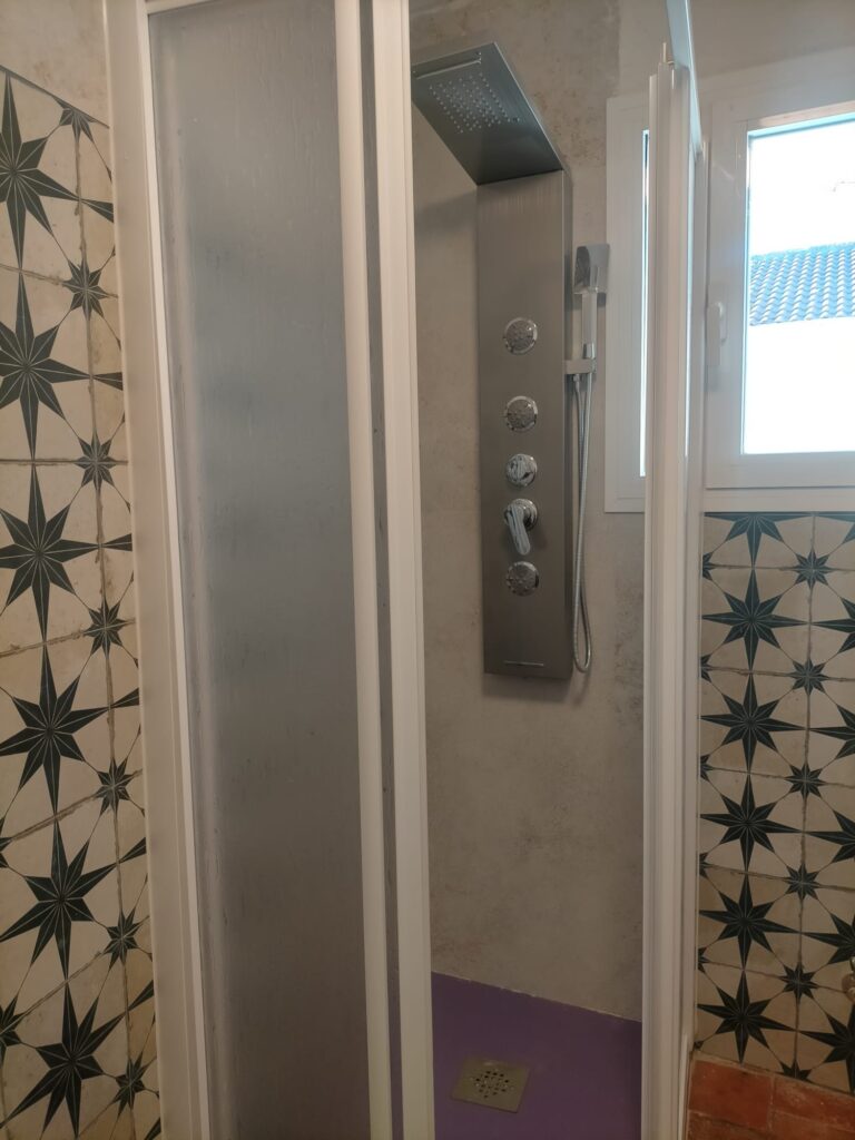 Una ducha con un sistema de ducha de lluvia y un panel de control con varios botones y un mango para el agua