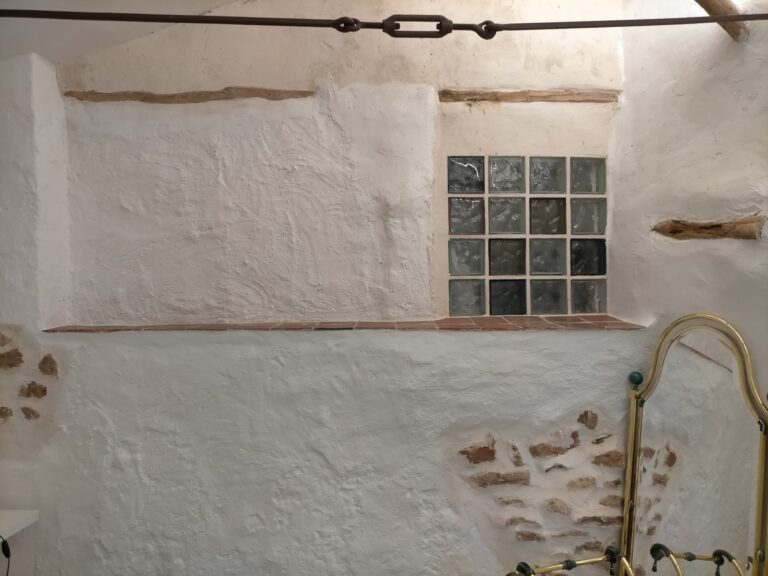Una ventana de vidrio de bloques en una pared blanca de una cocina de un alojamiento en Ciudad Real