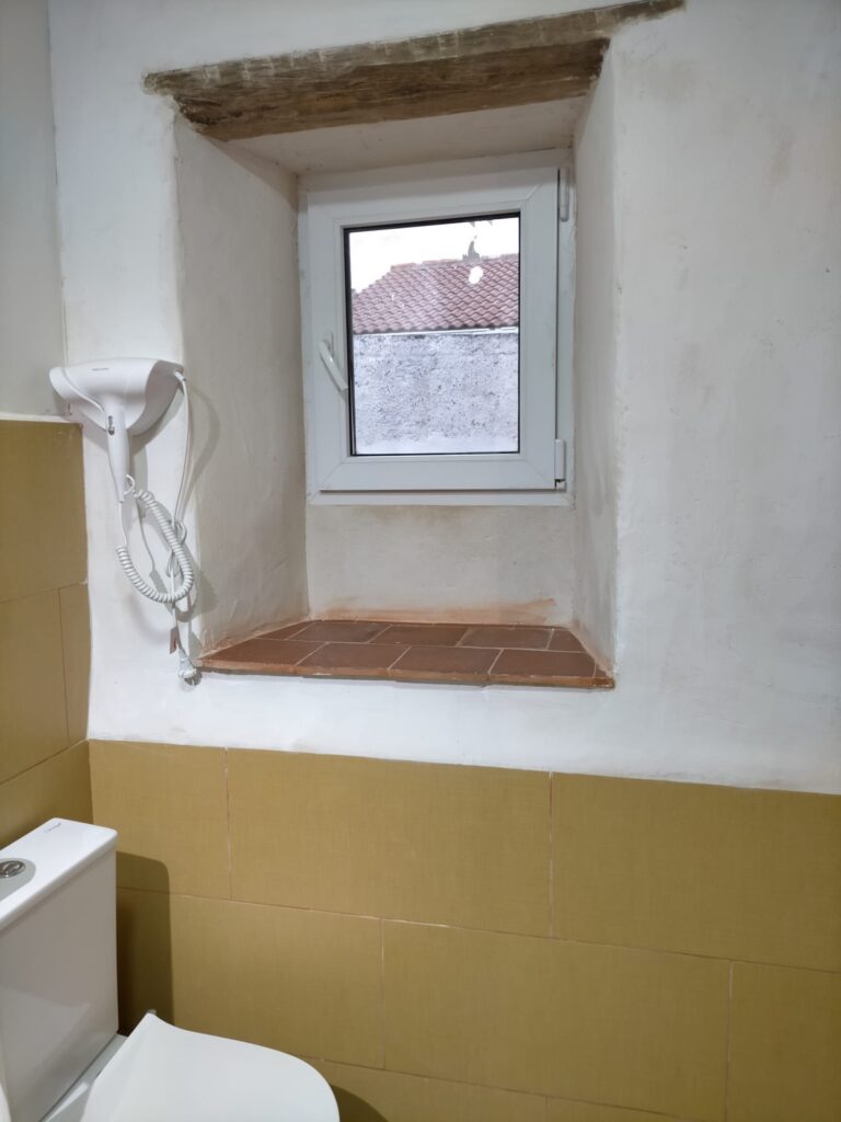 Una ventana con un marco blanco y un cristal rectangular, ubicada en una habitación de un alojamiento en Ciudad Real
