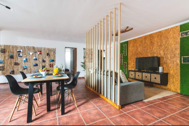 Comedor con mesa de madera y sillas negras, decorado con frutas y jugo de naranja, en un alojamiento en Arinaga
