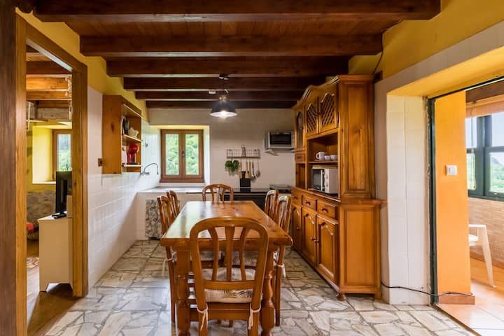 La cocina de esta casa rural en Cantabria, con su iluminación natural y mobiliario de madera, ofrece un ambiente