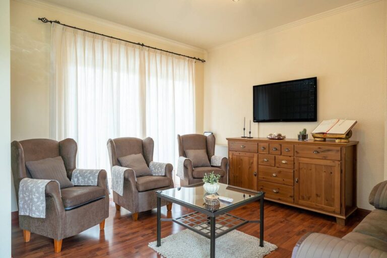 Un salón de un alojamiento en Asturias, con dos sillas de estilo clásico, un sofá, una mesa de centro y un televisor
