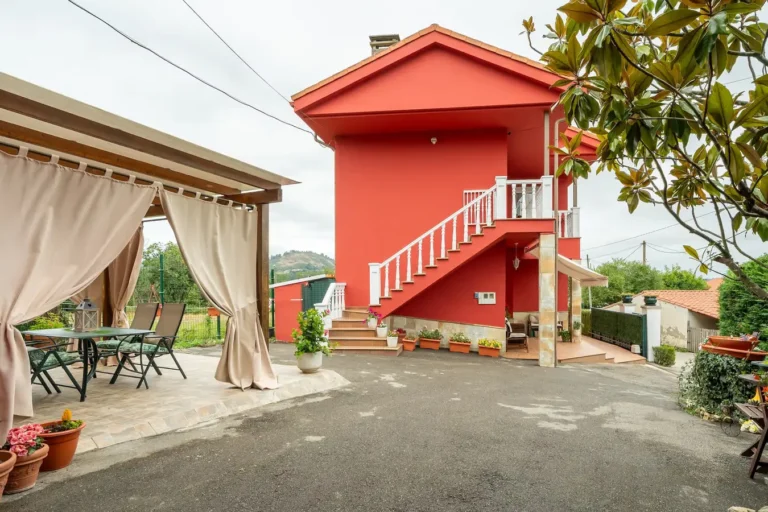 La terraza de un alojamiento en Asturias, con una mesa de jardín, sillas y una estructura de techo con cortinas