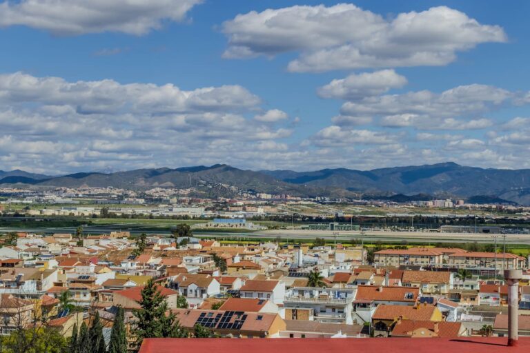 Una vista panorámica de la ciudad de Málaga, con una gran cantidad de casas y edificios en el primer plano, y una línea
