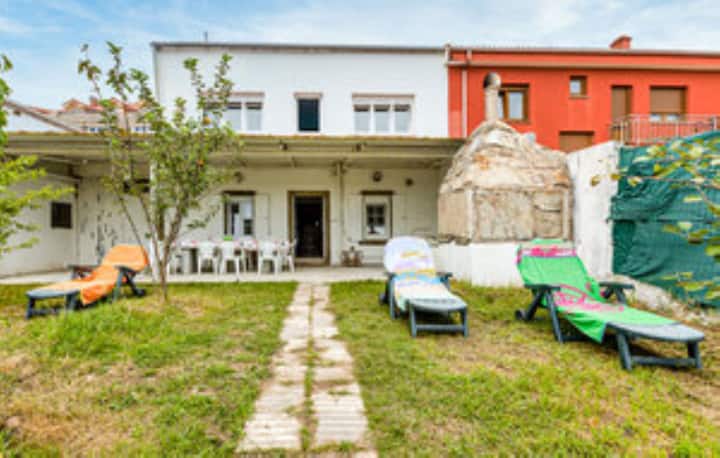 La terraza de un alojamiento en Fisterra, con cuatro tumbonas de colores y una pequeña mesa de plástico