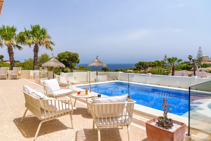 Una terraza con una piscina, dos sillas de jardín y una mesa, con vistas al mar y la costa de Alicante