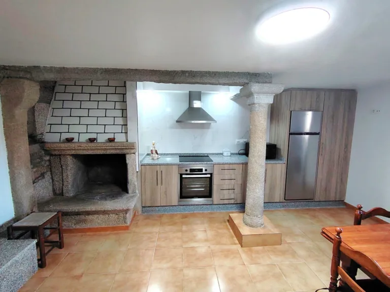 La cocina de esta casa rural en Muxia cuenta con un hogar de piedra, un extractor de cocina y un frigorifico