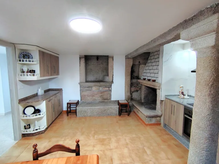 La cocina de esta casa rural en Muxia cuenta con un hogar de piedra y un espacio de trabajo con encimeras de granito