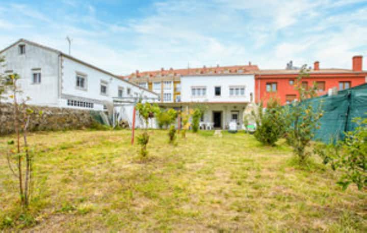 Un patio de una casa en Fisterra, con un césped seco y algunas plantas pequeñas