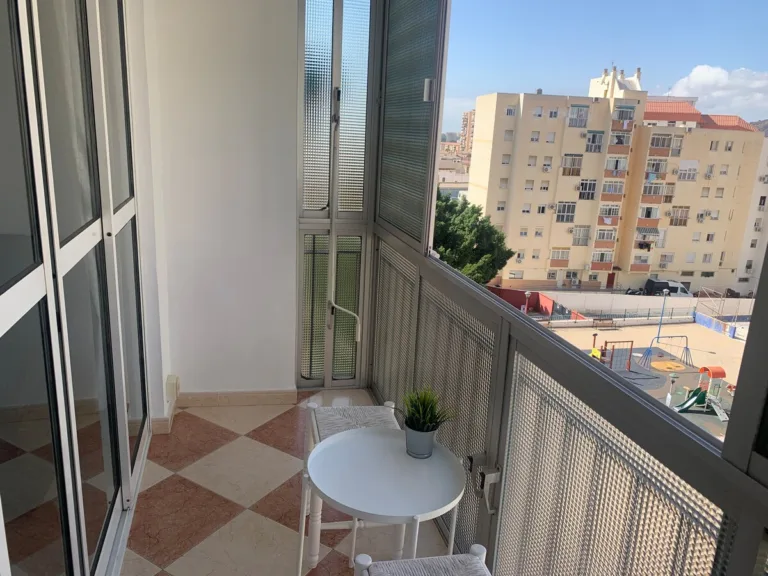 Una terraza con una mesa y dos sillas, y una vista de un edificio de apartamentos