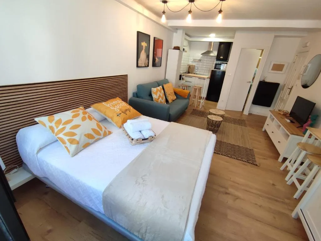 Una habitación con un sofá azul y una cama con dos almohadas amarillas
