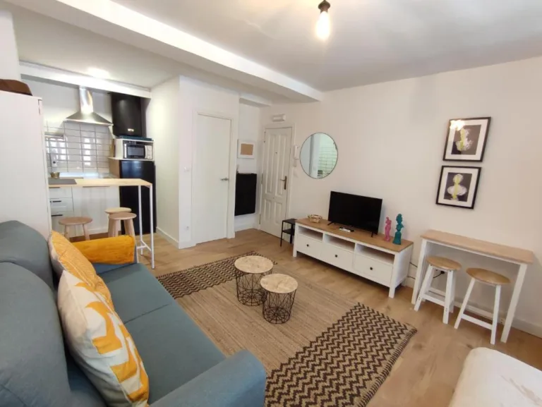 Un salón con un sofá azul y dos mesas de madera